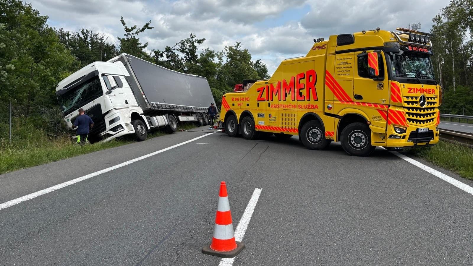 Żółty pojazd pomocy drogowej Zimmer na autostradzie obok białej ciężarówki, która zjechała do rowu